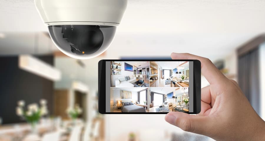 Homeowner holding smartphone with video feed from security cameras in San Diego