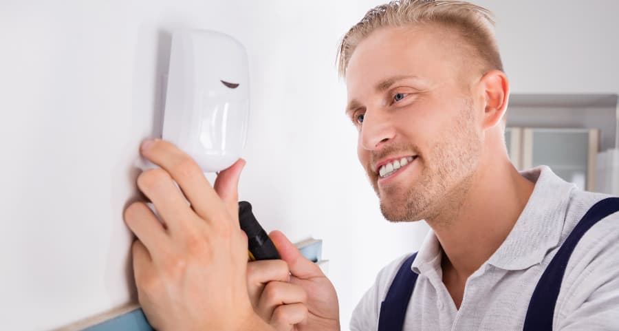 Man installing a motion detector in a living area